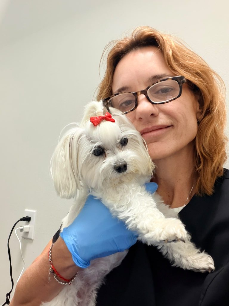 A caregiver holding a small white dog with affection